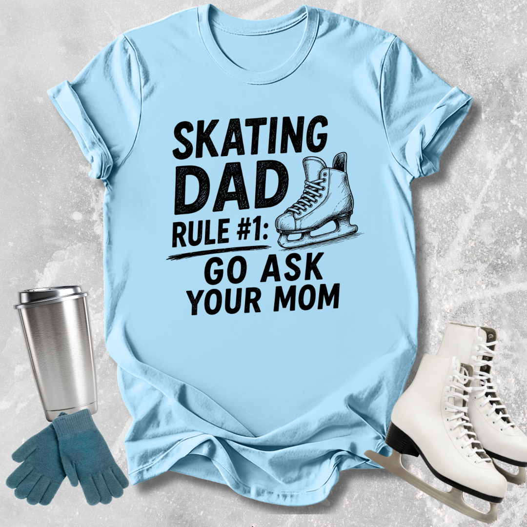 Light blue t-shirt with 'Skating Dad' text and graphics on a textured surface with accessories.