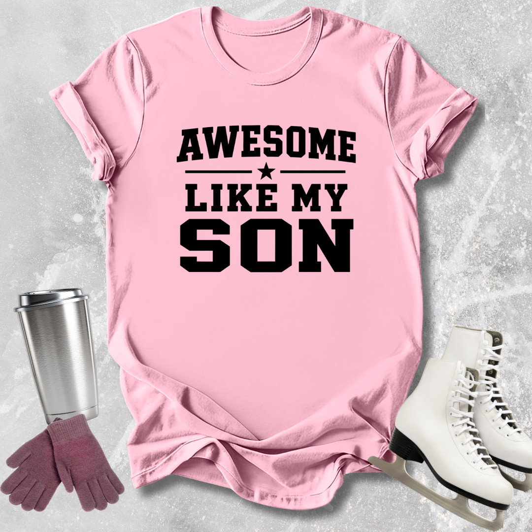 Pink t-shirt with 'Awesome Like My Son' text, next to a silver tumbler, pink gloves, and white skates on a light gray background.