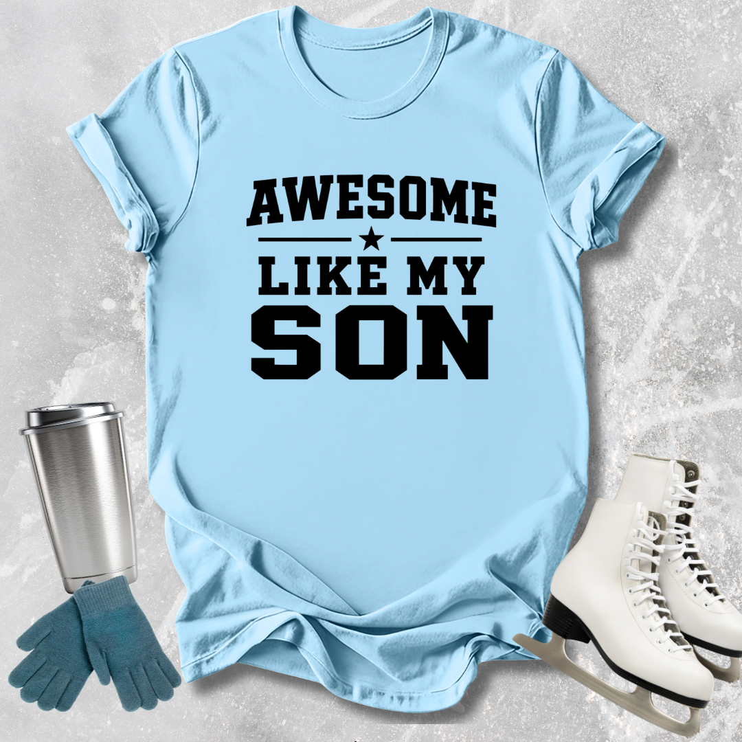 Light blue t-shirt with 'Awesome like my son' text, next to a silver tumbler, green gloves, and white skates on a textured surface.