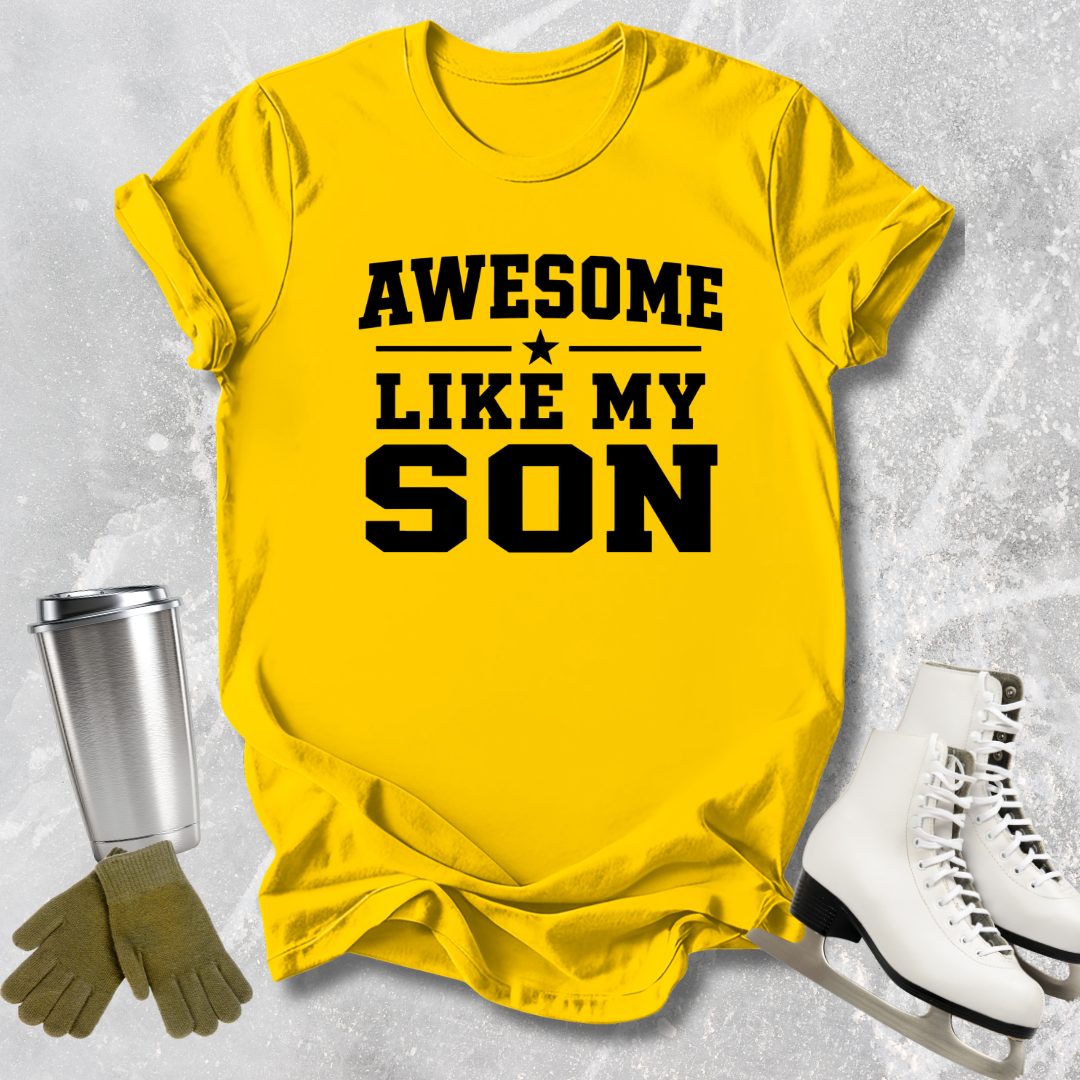 Yellow t-shirt with 'Awesome Like My Son' text, next to a silver tumbler, green gloves, and white skates on a textured gray background.