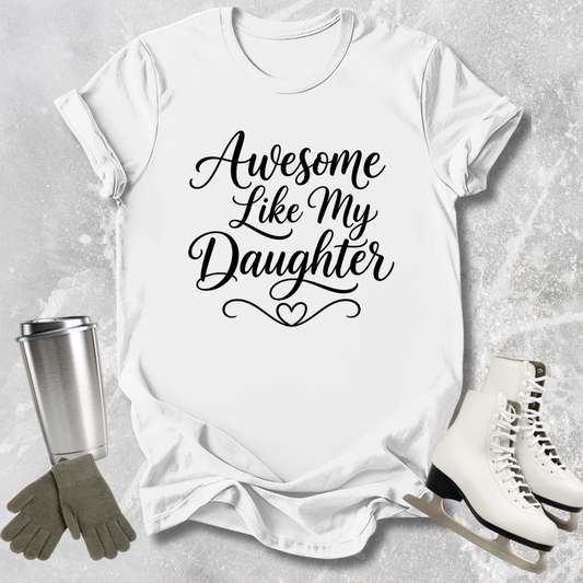 White t-shirt with 'Awesome Like My Daughter' text, next to a silver tumbler, green gloves, and white skates on a light gray background.