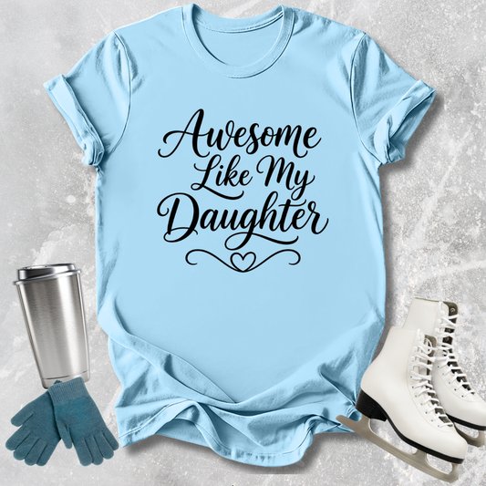 Light blue t-shirt with 'Awesome Like My Daughter' text, next to a silver tumbler, green gloves, and white skates on a textured surface.
