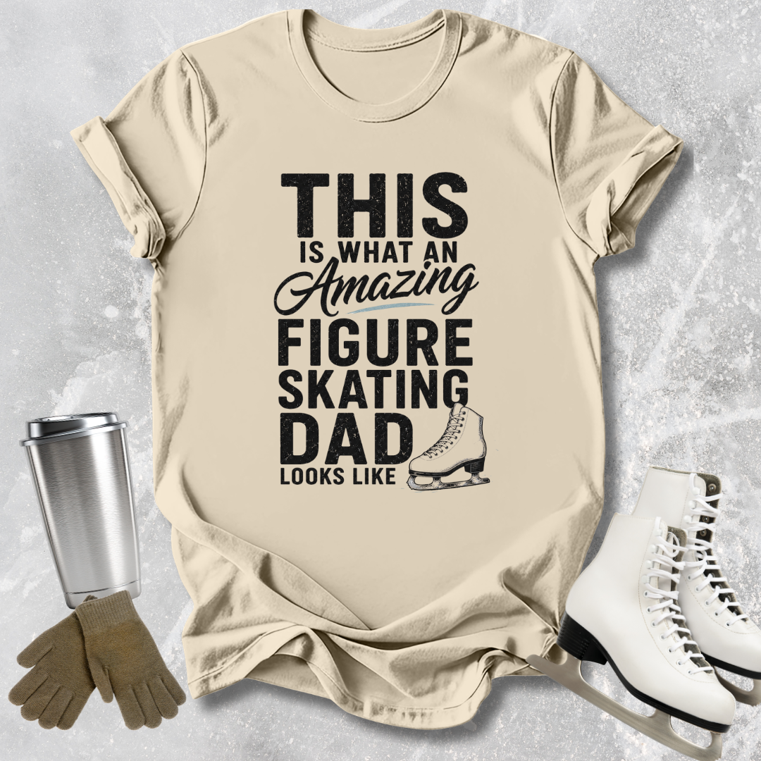 Beige t-shirt with text 'This is what an amazing figure skating dad looks like' on a textured surface with ice skates and gloves.