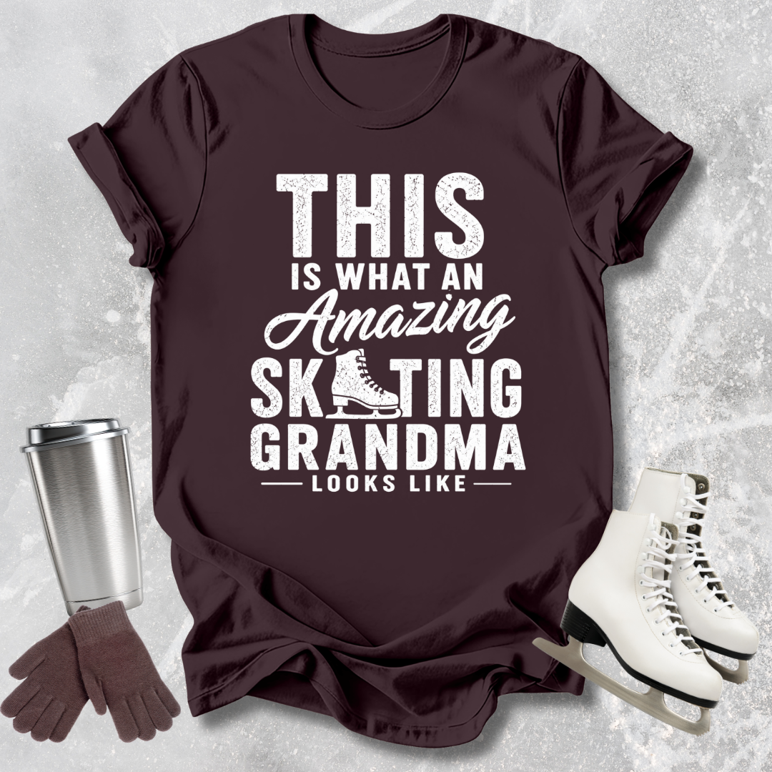 Brown t-shirt with 'Amazing Skating Grandma' text, next to ice skates and a tumbler on a textured surface.