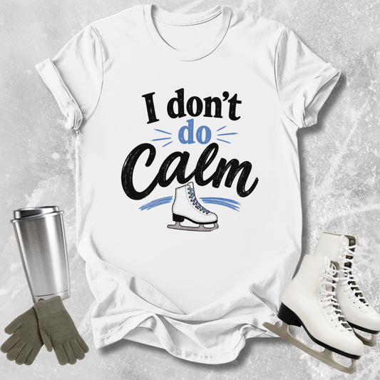 White t-shirt with 'I don't do Calm' text and ice skate graphic, surrounded by ice skates and a tumbler on a textured surface.