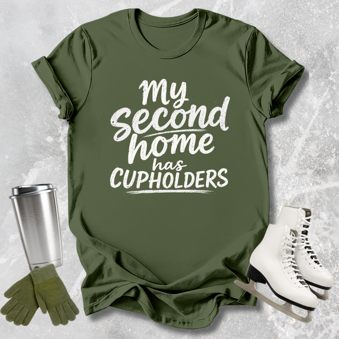 Green t-shirt with 'My second home has cupholders' text, paired with a silver tumbler, green gloves, and white skates on a textured gray background.