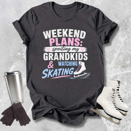 Black t-shirt with text 'Weekend Plans: spoiling my grandkids & watching skating' on a textured surface with ice skates and a travel mug.