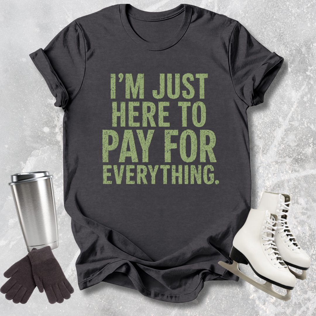 Dark gray t-shirt with green text 'I'm just here to pay for everything.' on a textured surface with accessories.