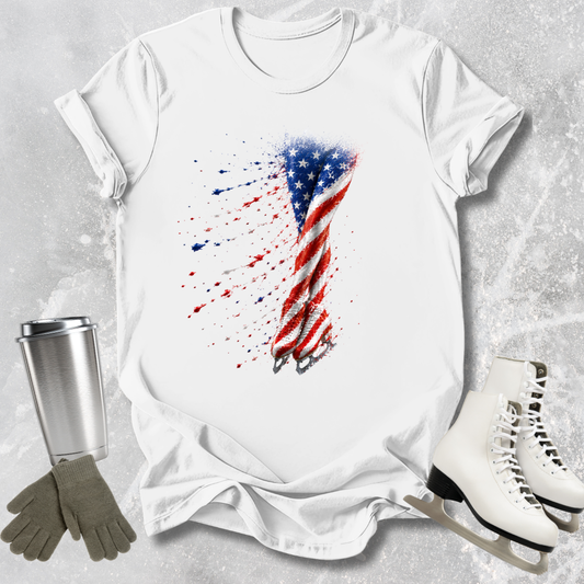 White t-shirt with American flag design, next to a silver tumbler, gray gloves, and white skates on a textured surface.