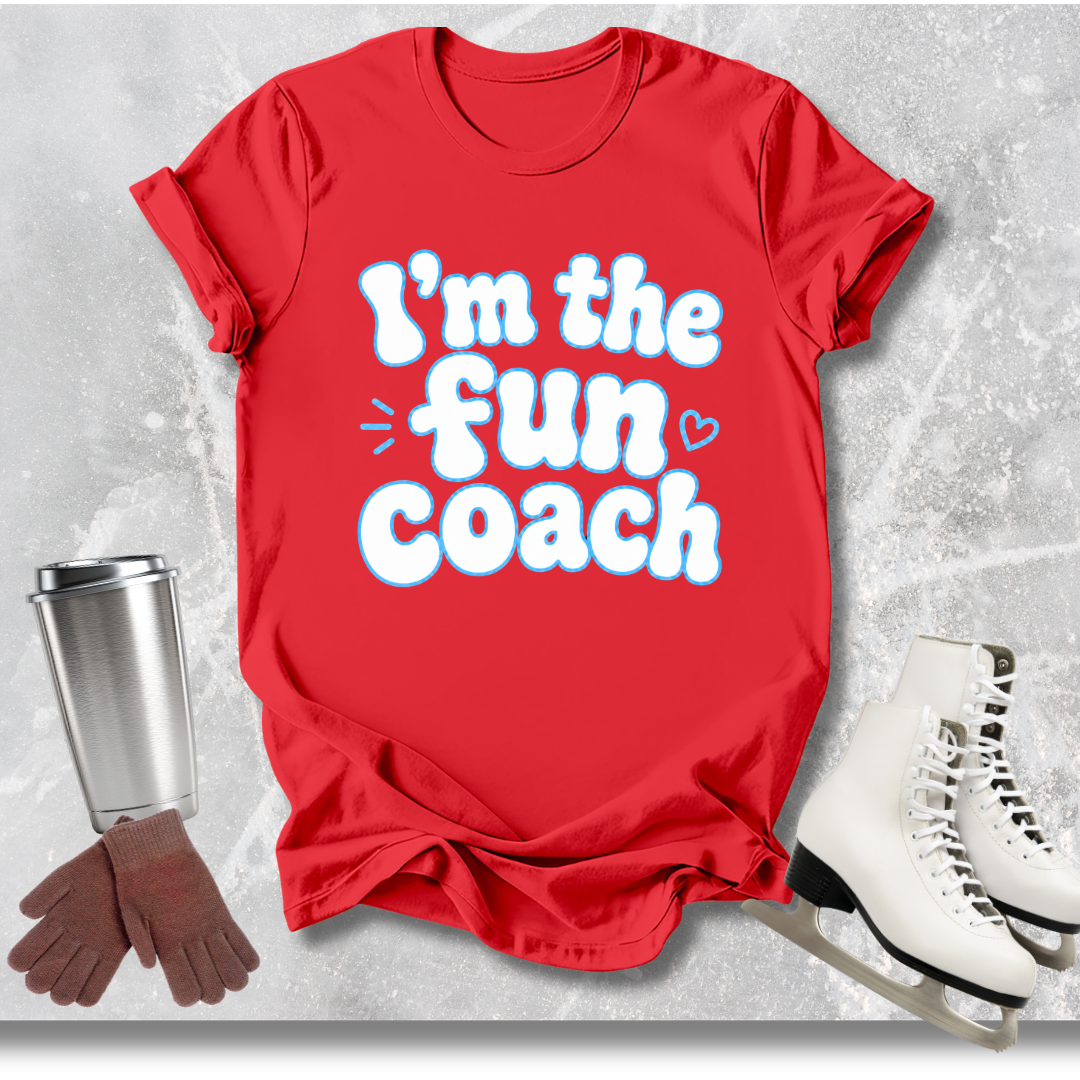 Red t-shirt with 'I'm the fun coach' text, next to a silver tumbler, brown gloves, and white skates on a light gray background.