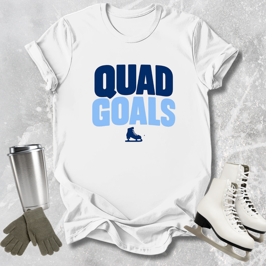 White t-shirt with 'Quad Goals' text, ice skates, gloves, and a tumbler on a textured gray background
