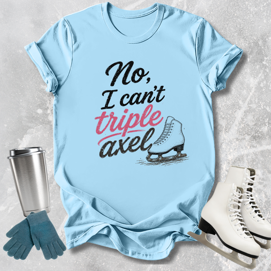 Light blue t-shirt with 'No, I can't triple Axel' text, next to ice skates and a tumbler on a textured surface.