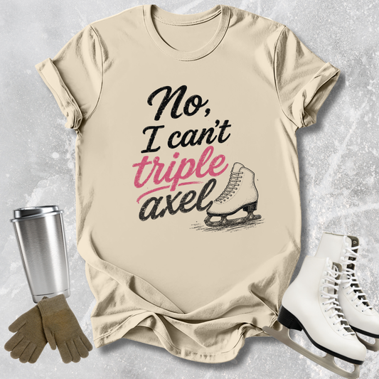 Beige  t-shirt with 'No, I can't triple Axel' text, ice skates, gloves, and a tumbler on a textured surface.