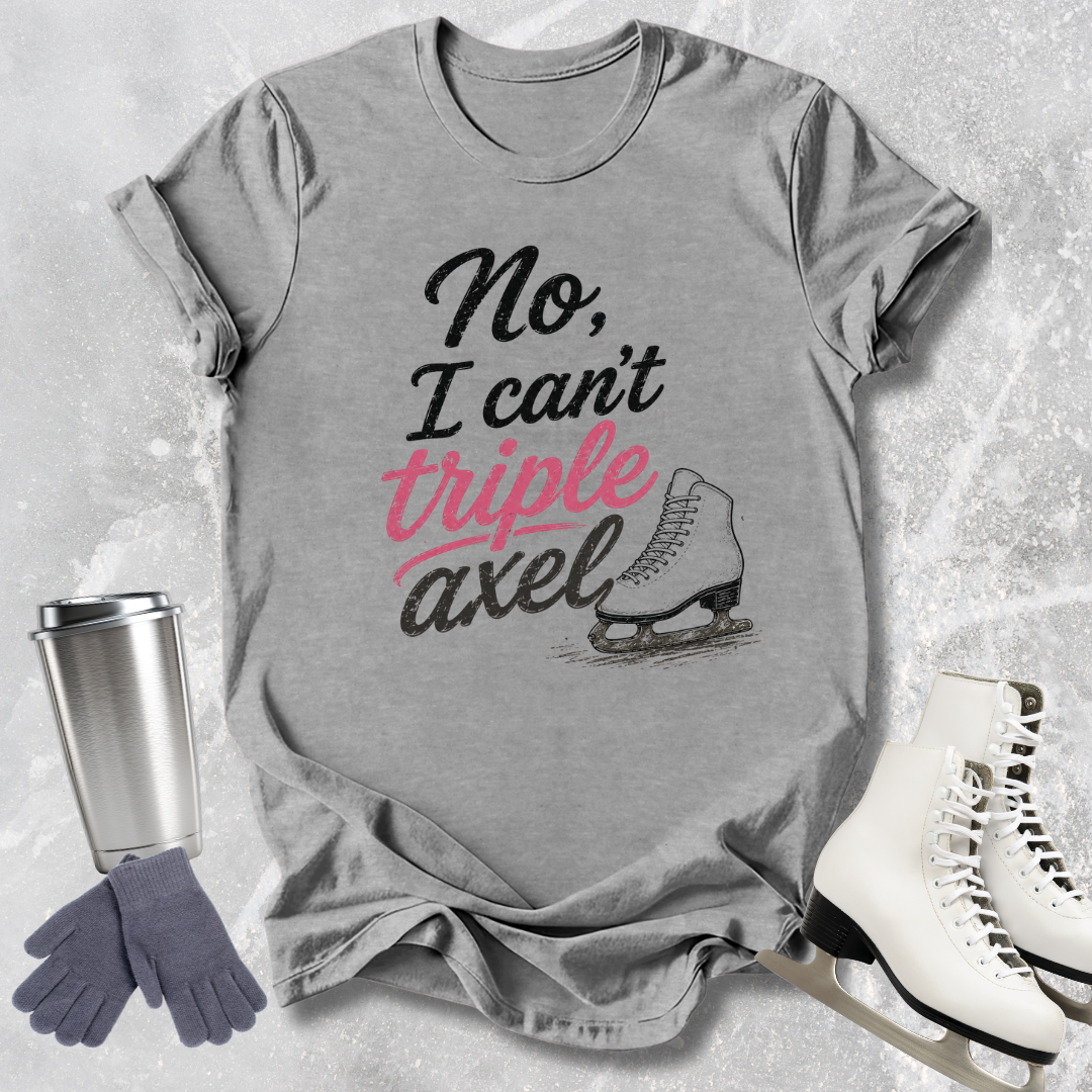 Gray t-shirt with 'No, I can't triple Axel' text, ice skates, gloves, and a tumbler on a textured surface.