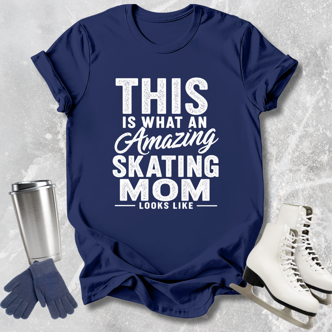 Navy blue t-shirt with 'Amazing Skating Mom' text, next to a silver tumbler, gloves, and white skates on a textured gray background.