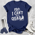 Navy t-shirt with 'no, I can't do a quad' text and ice skate graphic on a textured gray background.