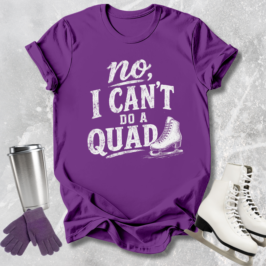 Purple t-shirt with 'no, I can't do a quad' text and graphic on a textured surface with ice skates and a tumbler.