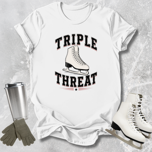 White t-shirt with 'Triple Threat' graphic, ice skates, gloves, and a tumbler on a textured surface.