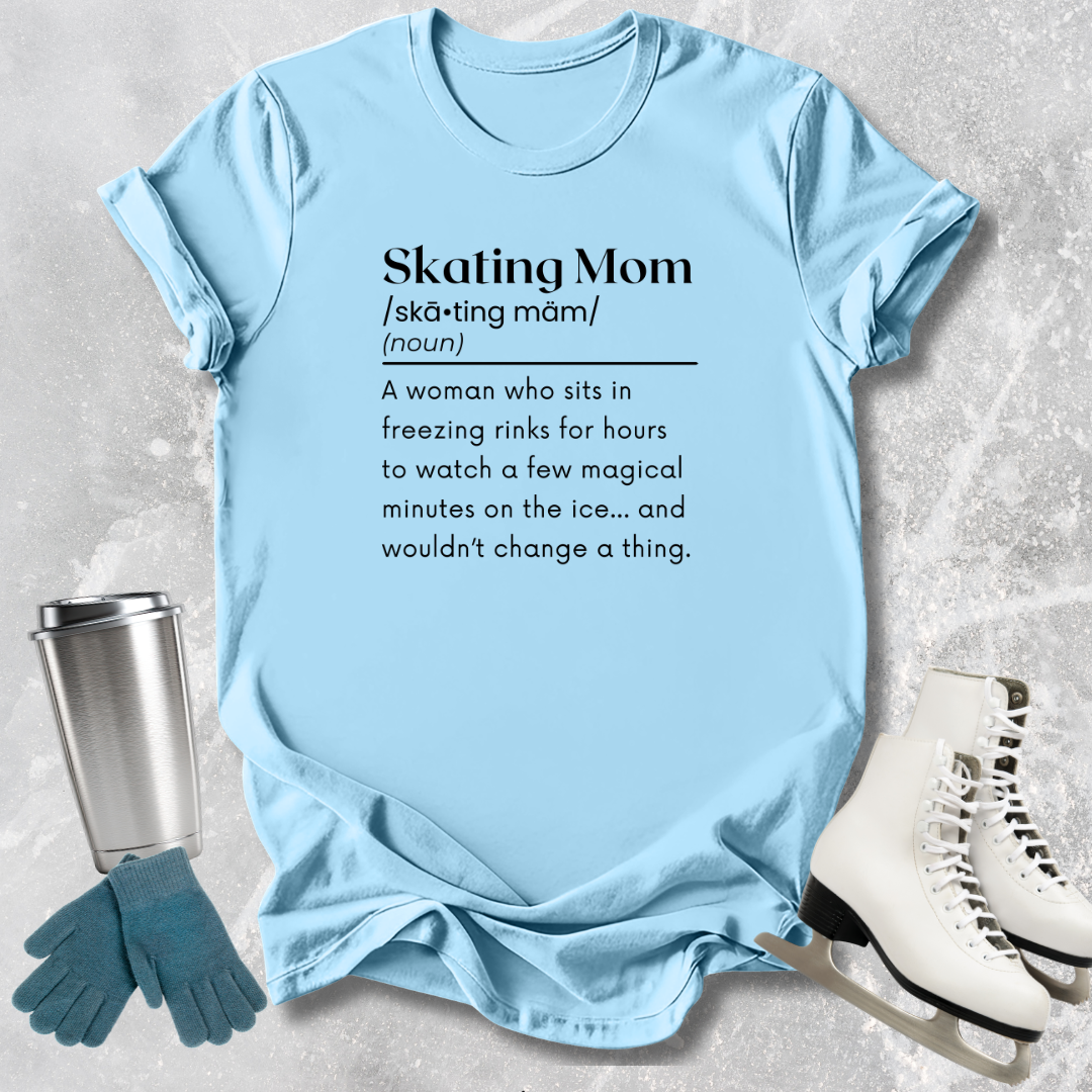 Light blue t-shirt with 'Skating Mom' definition text, placed on a textured surface with ice skates and gloves.