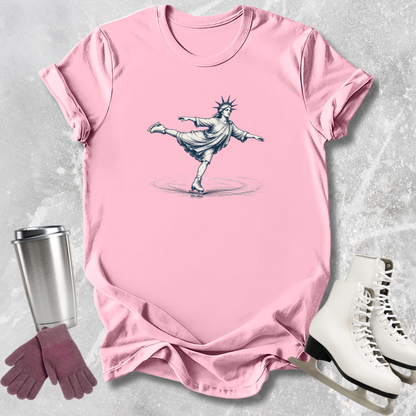 Pink t-shirt with a graphic design of the Statue of Liberty, placed on a textured surface with a tumbler, gloves, and skates.