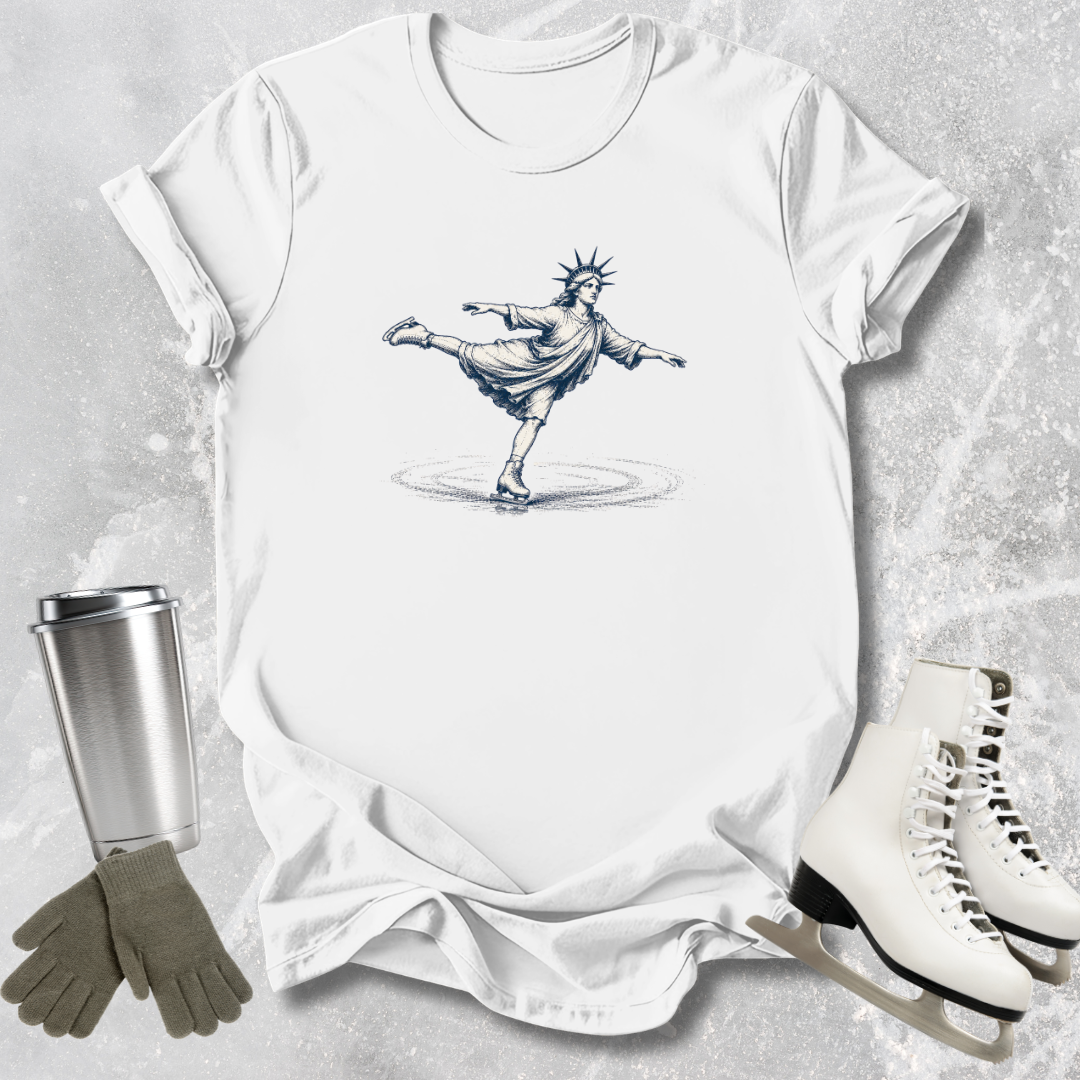 White t-shirt with a graphic design of a skater, next to white skates, gray gloves, and a silver tumbler on a textured surface.