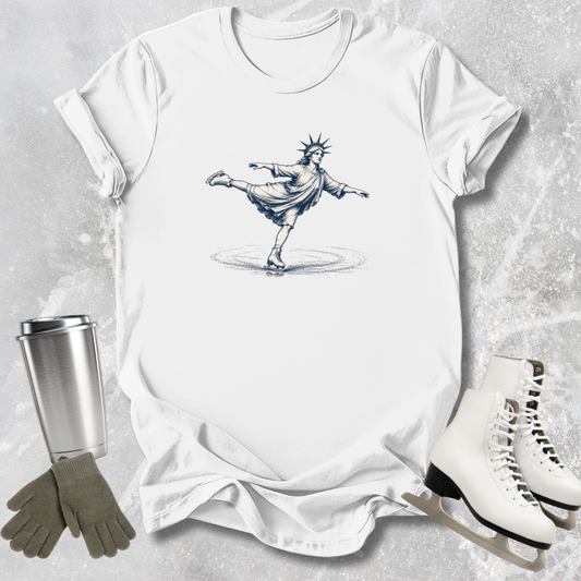 White t-shirt with a graphic design of a skater, next to white skates, gray gloves, and a silver tumbler on a textured surface.