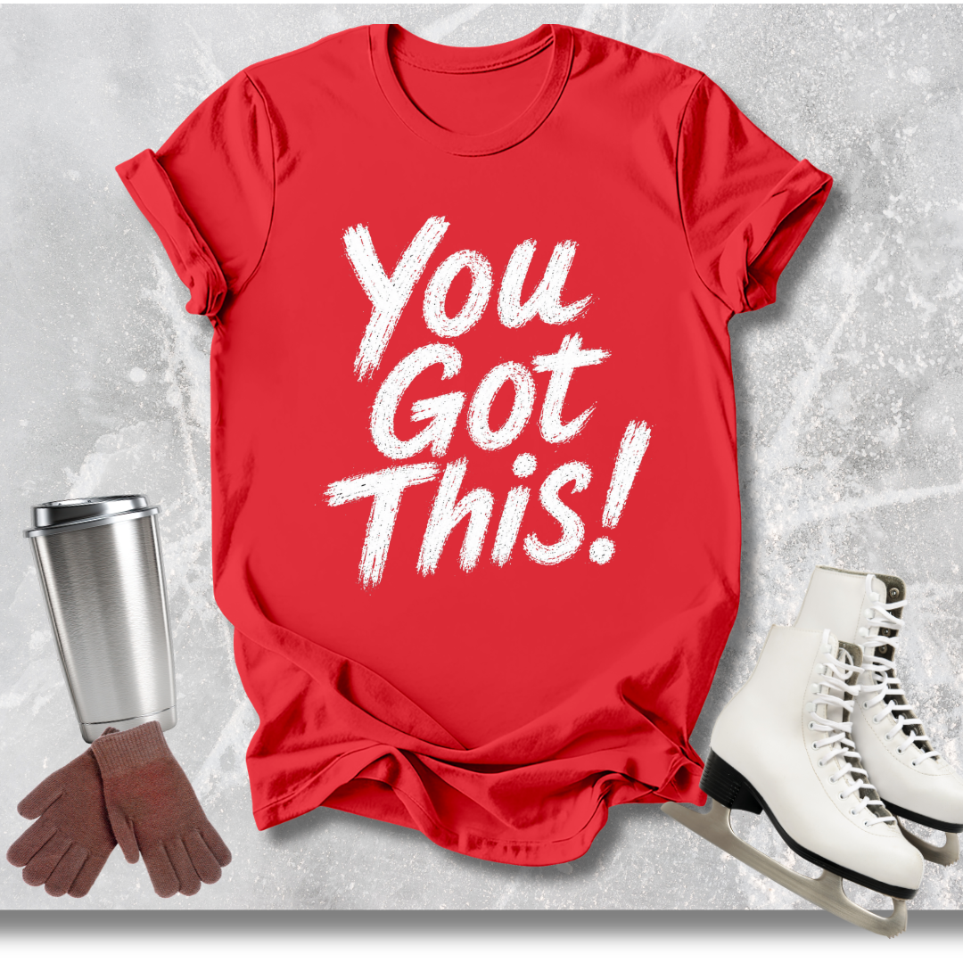 Red t-shirt with 'You Got This!' text, white skates, brown gloves, and silver cup on a textured gray background