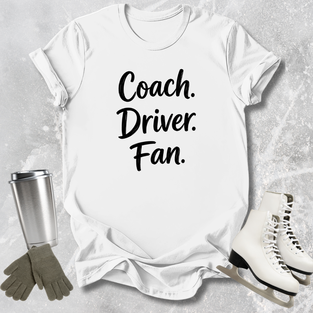 White t-shirt with 'Coach. Driver. Fan.' text, surrounded by ice skates, gloves, and a tumbler on a gray background.