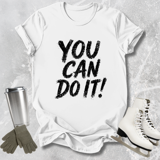 White t-shirt with 'You Can Do It!' text, silver tumbler, gray gloves, and white skates on a light gray background