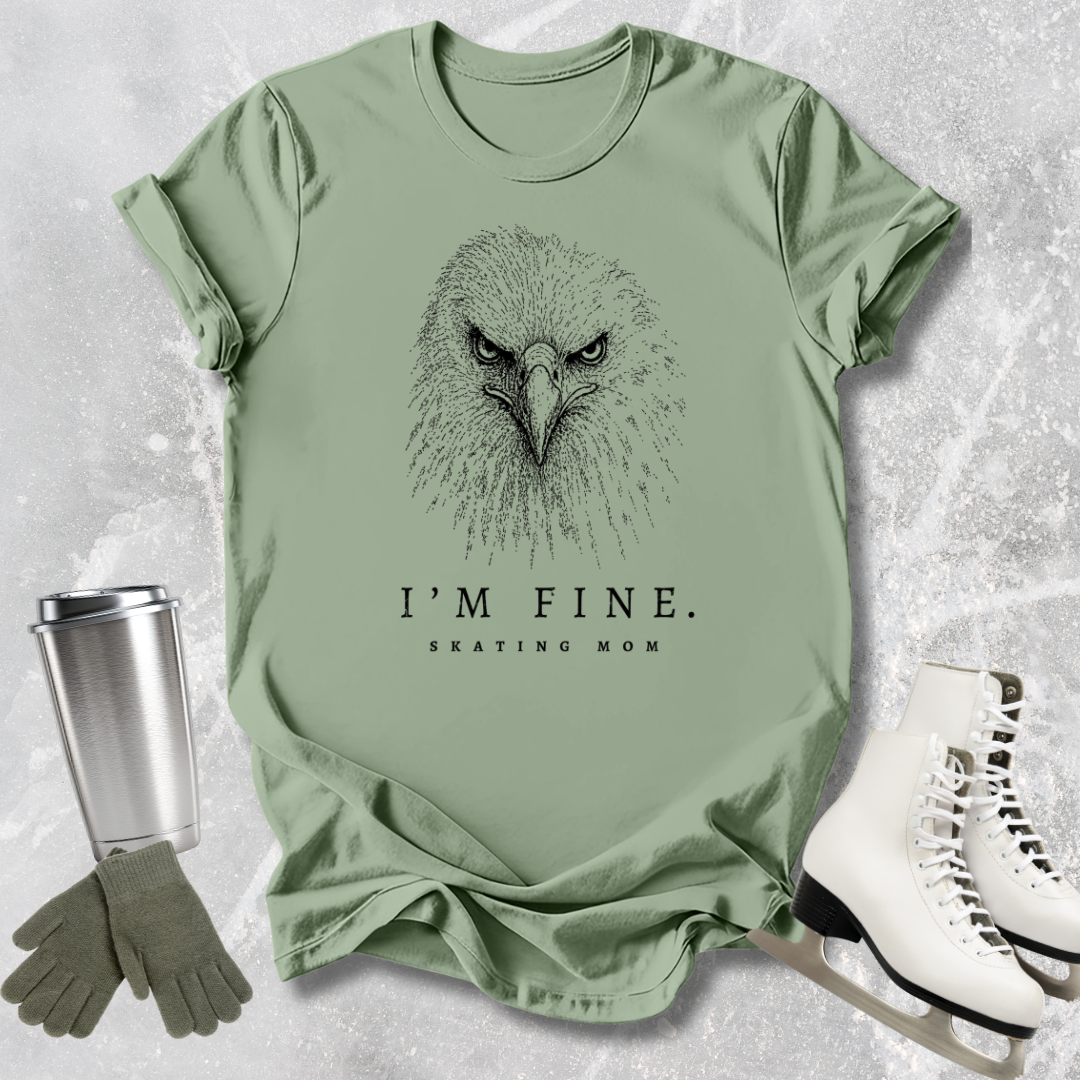 Green t-shirt with eagle graphic and 'I'm Fine. Skating Mom' text, paired with a silver tumbler, green gloves, and white skates on a textured surface.
