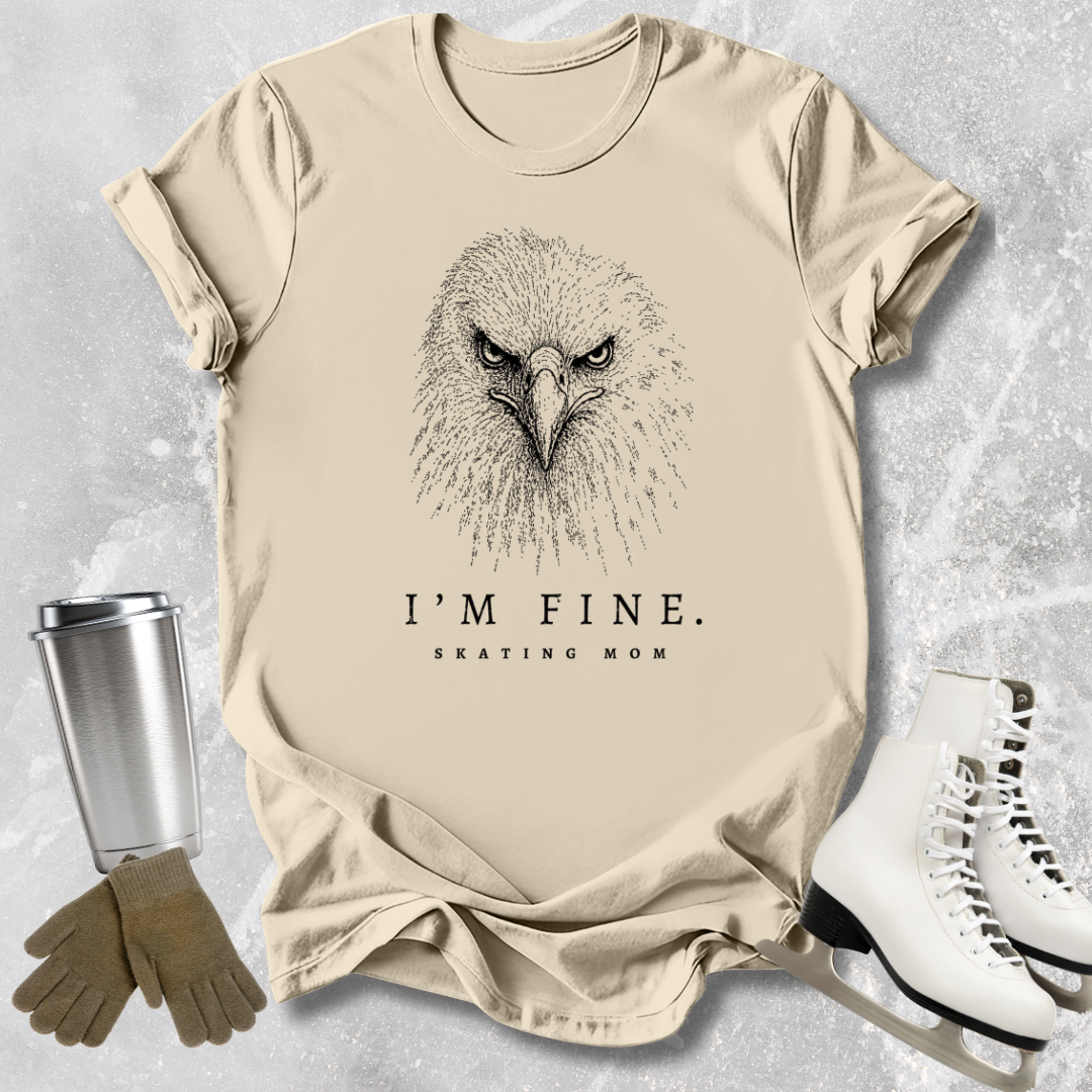 Beige t-shirt with an eagle graphic and text 'I'm fine. Skating mom' on a textured surface.