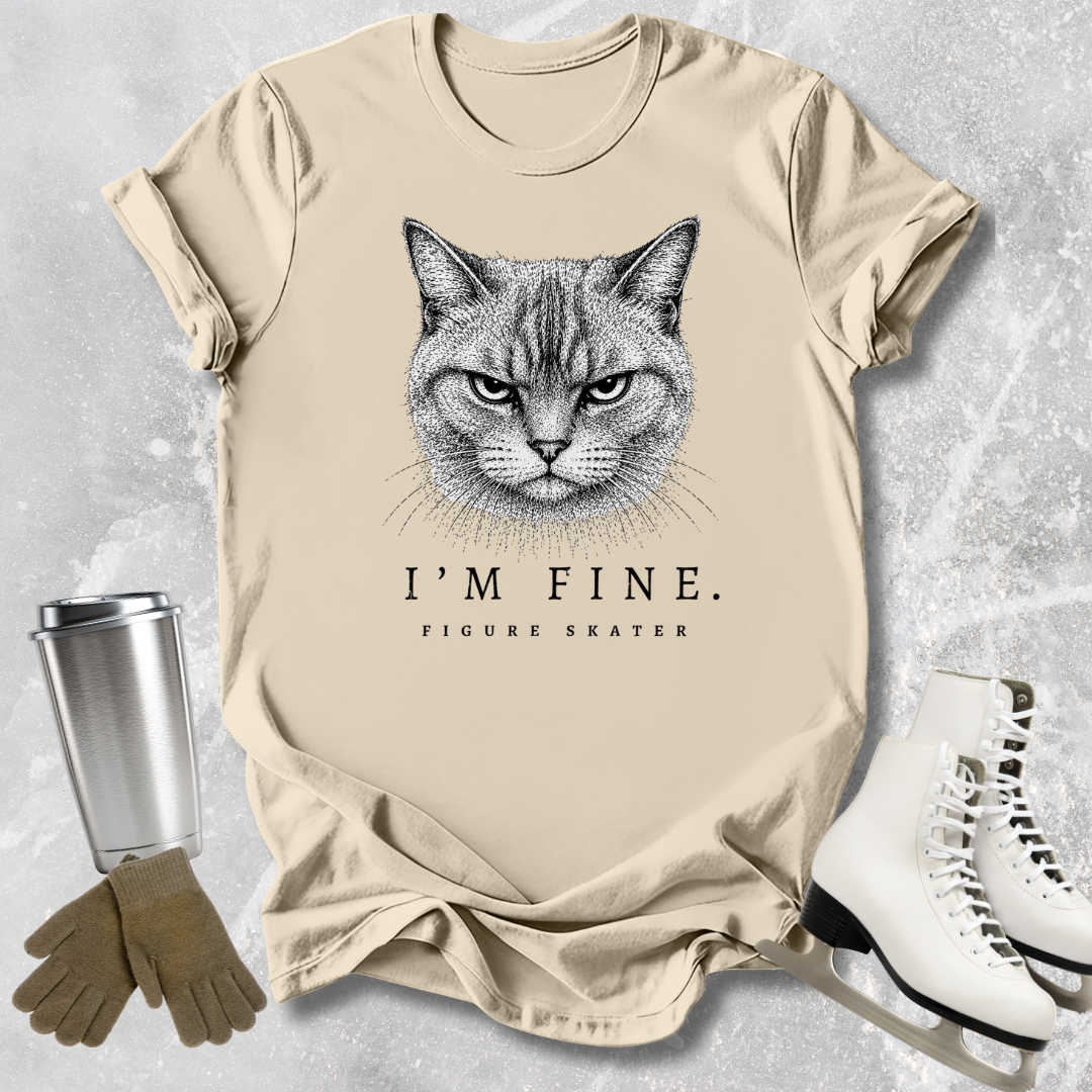 Beige t-shirt with a cat graphic and text, placed on a textured surface with accessories like a tumbler, gloves, and skates.