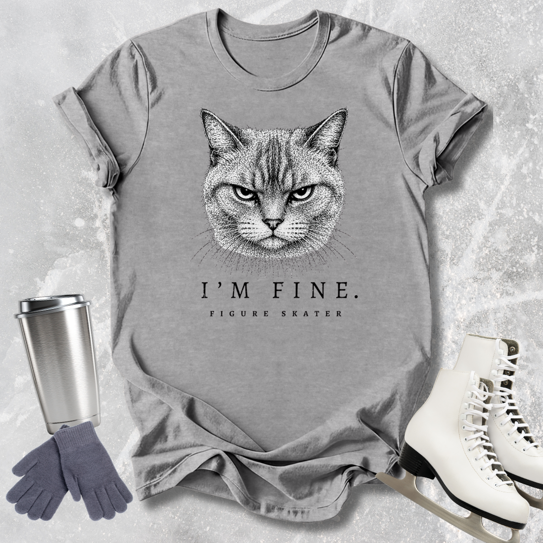 Gray t-shirt with a cat graphic and text, placed on a textured surface with a travel mug, gloves, and skates.