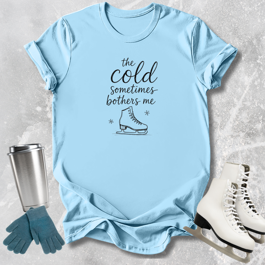 Light blue t-shirt with text and graphics on a textured surface with accessories.