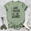 Green t-shirt with 'I came. Skated. I hit the boards.' text, paired with ice skates and a tumbler on a textured surface.