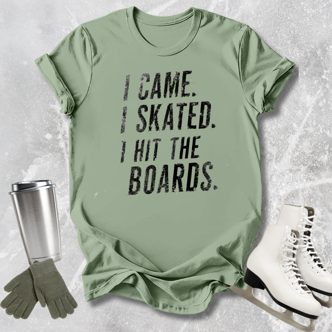 Green t-shirt with 'I came. Skated. I hit the boards.' text, paired with ice skates and a tumbler on a textured surface.