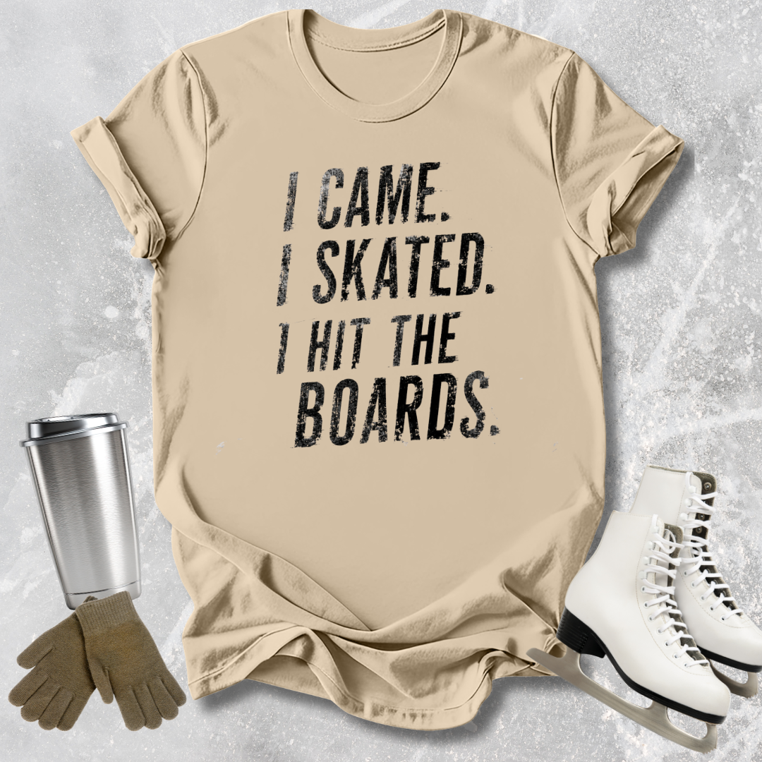 Beige t-shirt with 'I Came. I Skated. I Hit the Boards.' text, next to ice skates and a tumbler on a textured surface.