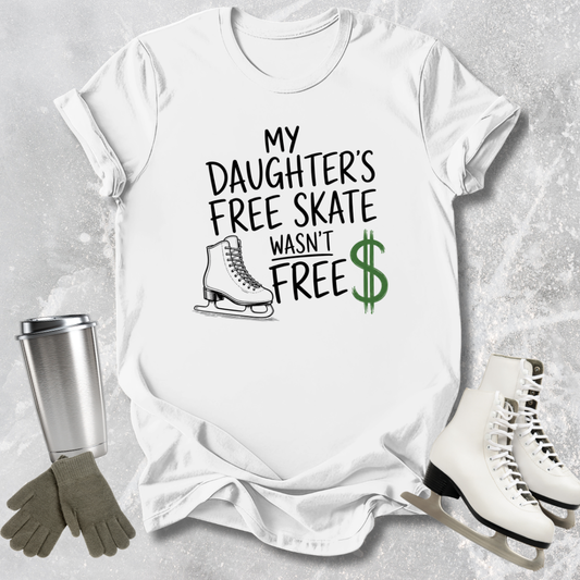 White t-shirt with text 'My Daughter's Free Skate Wasn't Free' on a textured gray background, with ice skates and gloves.