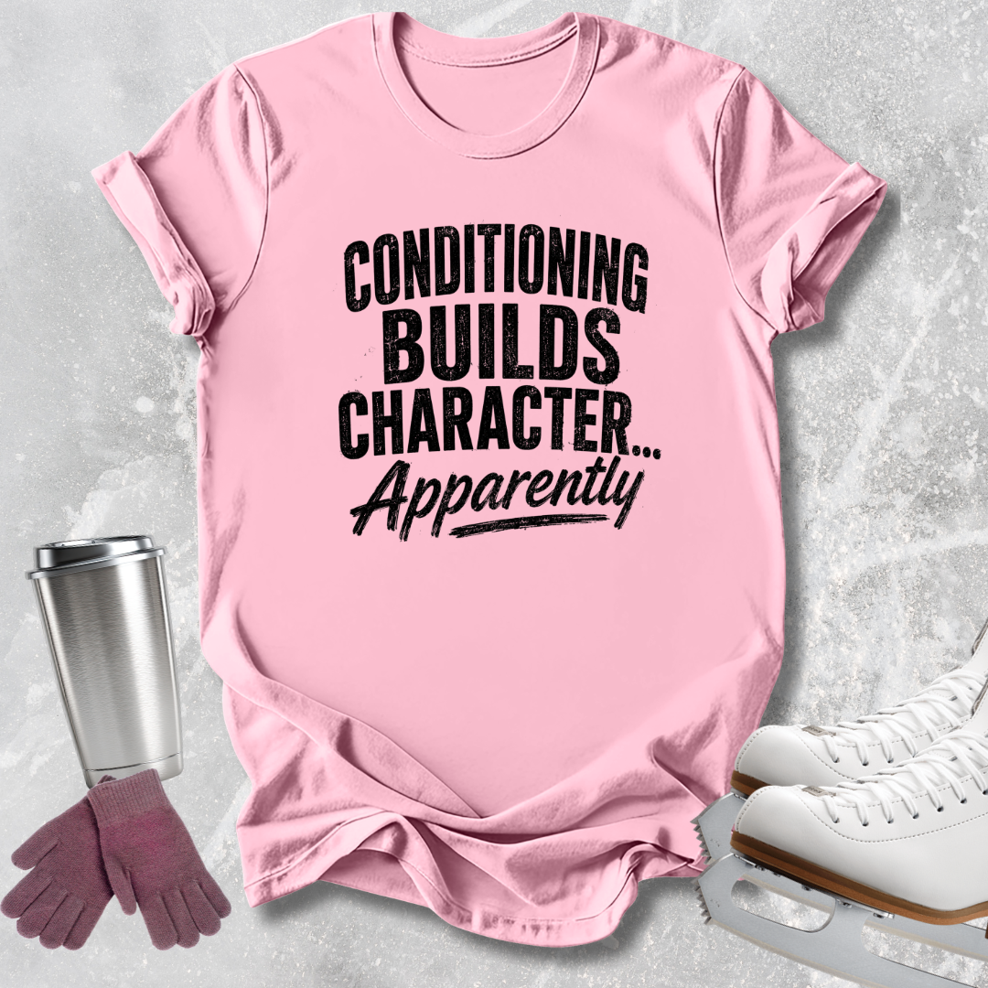 A pink short-sleeve graphic T-shirt laid flat on a light gray textured surface, with black text reading 'CONDITIONING BUILDS CHARACTER.