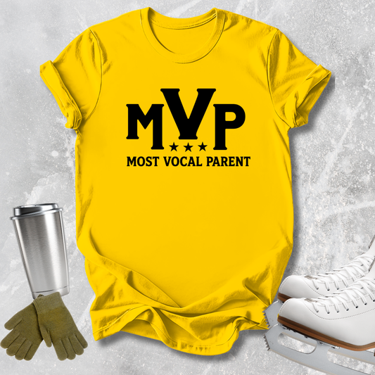 A bright yellow graphic t-shirt featuring the black text 'MVP MOST VOCAL PARENT' with stars, styled in a flat-lay arrangement with ice skates, gloves, and a metal cup on a light gray textured background.