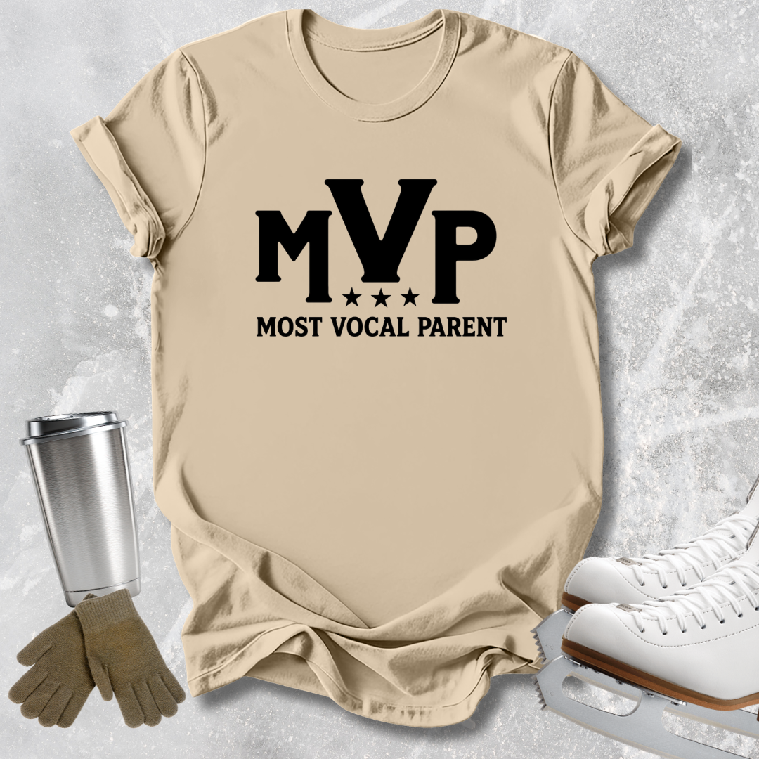 A beige graphic t-shirt with 'MVP MOST VOCAL PARENT' printed in black, styled in a flat-lay with ice skates, gloves, and a tumbler on a textured gray background.