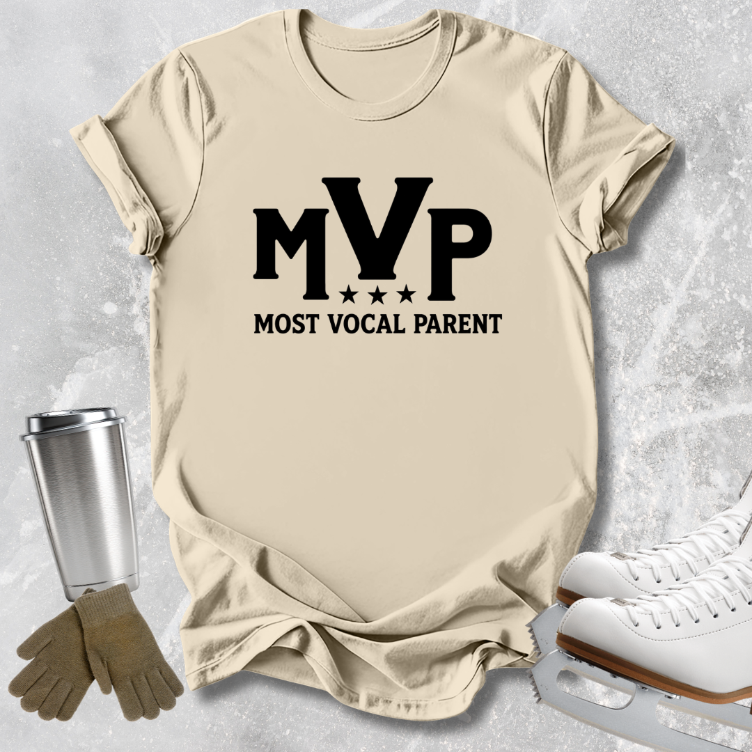 A beige graphic t-shirt with 'MVP MOST VOCAL PARENT' printed in black, styled in a flat-lay with ice skates, gloves, and a tumbler on a textured gray background.