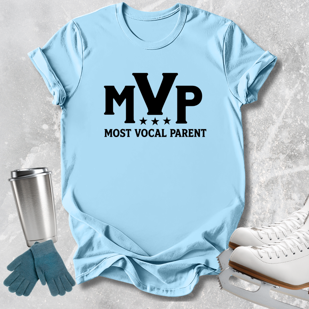 A light blue graphic t-shirt with 'MVP MOST VOCAL PARENT' printed in black, styled in a flat-lay with ice skates, gloves, and a tumbler on a textured gray background.