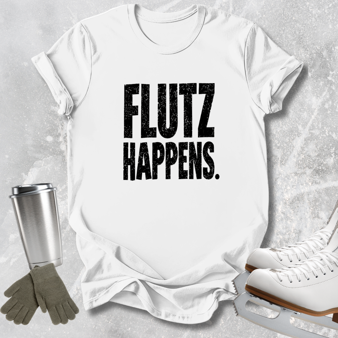 A white short-sleeve T-shirt laid flat on a light gray textured background, printed with the phrase 'FLUTZ HAPPENS.' in large distressed black letters.