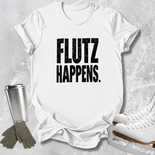 A white short-sleeve T-shirt laid flat on a light gray textured background, printed with the phrase 'FLUTZ HAPPENS.' in large distressed black letters.