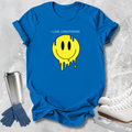 A bright blue short-sleeve T-shirt laid flat on a light textured surface, featuring a yellow dripping smiley face graphic with the text 'I LOVE CONDITIONING' above it. Blue gloves and white ice skates are placed around the shirt as styling props.