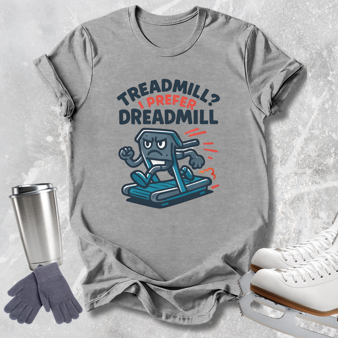 A heather gray graphic t-shirt laid flat on a light gray textured background, featuring a cartoon treadmill character and the text 'TREADMILL? I PREFER DREADMILL'. Surrounding props include a stainless steel travel mug, gray gloves, and white ice skates.
