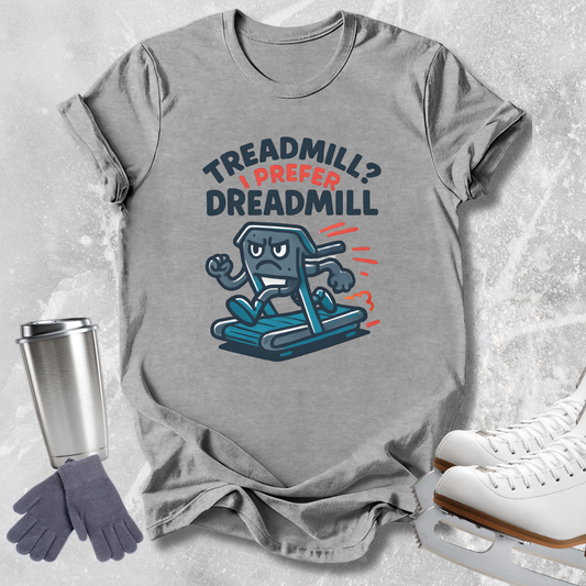 A heather gray graphic t-shirt laid flat on a light gray textured background, featuring a cartoon treadmill character and the text 'TREADMILL? I PREFER DREADMILL'. Surrounding props include a stainless steel travel mug, gray gloves, and white ice skates.