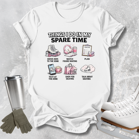 A white graphic t-shirt laid flat on a light gray textured background, surrounded by ice skating props including white ice skates, a silver tumbler, and a pair of gray gloves. The t-shirt features a black and pink graphic with the text 'THINGS I DO IN MY SPARE TIME' and six small illustrations with labels related to ice skating.