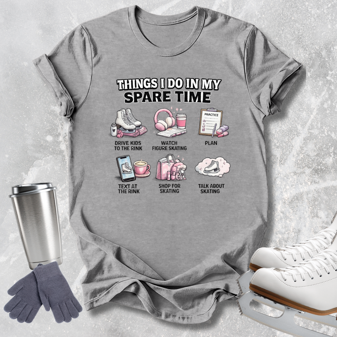 A gray graphic t-shirt laid flat on a light gray textured background, surrounded by ice skating accessories including white ice skates, a silver travel mug, and gray gloves. The t-shirt features a white and pink graphic with the text 'THINGS I DO IN MY SPARE TIME' and six small illustrations with labels.